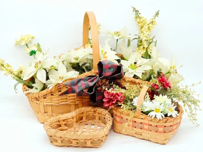 Set of three woven baskets, including two filled with artificial floral arrangements and one empty heart-shaped basket.
