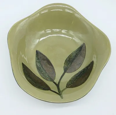 Mid-century modern ceramic bowl featuring an organic, tri-lobed shape and a hand-painted leaf motif in earthy green and brown tones.