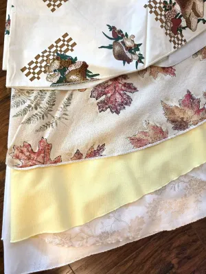 Assorted vintage tablecloths, including a 1970s mushroom and checkerboard print, an autumn leaf pattern, a solid yellow linen, and a...