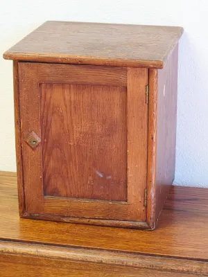Antique rustic pine tabletop cabinet featuring a single panel door with a diamond-shaped keyhole surround.