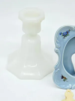 Vintage white milk glass candlestick holder with a hexagonal base, shown next to a light blue ceramic piece with floral details.