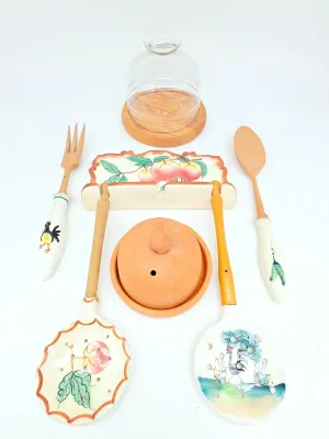Assorted vintage kitchenware including hand-painted ceramic and wooden utensils, a wall-mounted utensil rack with peach motif, a...
