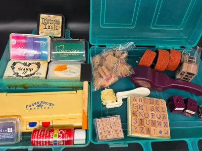 Assorted crafting and rubber stamping supplies, including wooden alphabet stamps, ink pads from brands like VersaColor and Distress Ink,...
