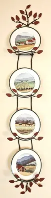 Four-tier vertical metal plate rack with leaf accents, holding decorative ceramic plates featuring rustic countryside and vineyard...