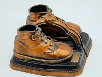 Pair of vintage bronzed baby shoe bookends mounted on black and bronze-toned bases.