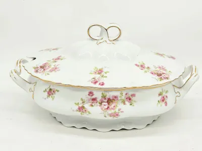 Haviland Limoges porcelain covered tureen featuring a delicate pink rose pattern, scalloped edges, and gold-gilded accents on the handles...