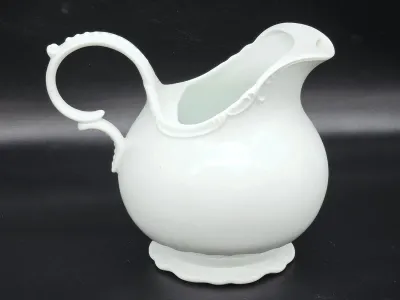 Vintage white porcelain pitcher featuring a bulbous body, scalloped pedestal base, and an ornate, scrolled handle.