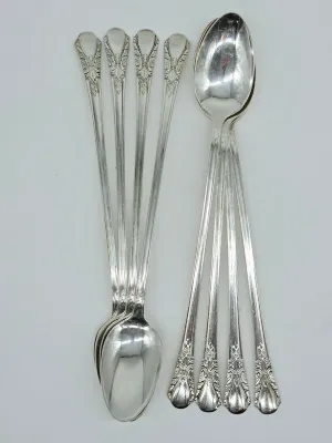 Eight silverplate iced tea spoons featuring an ornate floral pattern on the handles, showing light surface wear and tarnish.