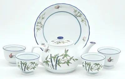 Vintage Japanese porcelain tea set featuring a hand-painted bamboo and butterfly motif, including a teapot, four cups, and a matching...