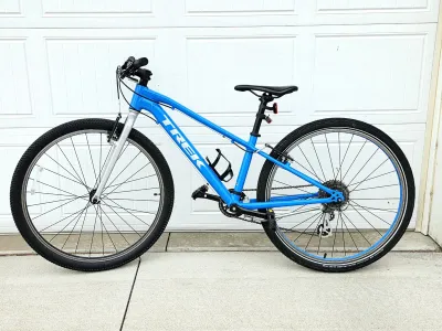 Trek multi-speed hybrid bicycle in bright blue, featuring a lightweight aluminum frame, front suspension fork, and a water bottle cage.