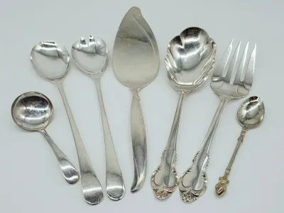 Assorted vintage silver-plated serving utensils, including a pie server, salad servers, a shell-bowl spoon, a cold meat fork, and ladles,...