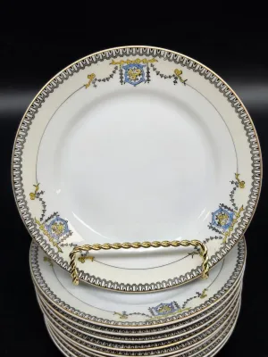 Stack of vintage Noritake porcelain plates featuring a delicate cream rim, gold trim, and a blue and yellow floral garland motif.