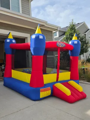 Blast Zone inflatable bounce house castle in vibrant red, blue, and yellow, featuring a small entry slide and mesh safety netting.