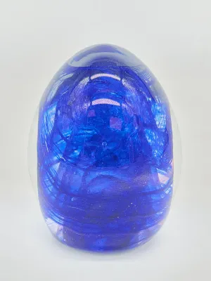 Egg-shaped art glass paperweight featuring a vibrant cobalt blue swirl interior encased in clear glass.