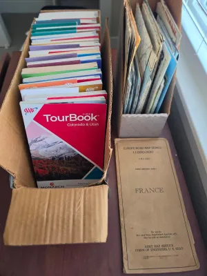 Collection of vintage travel ephemera, including a box of AAA TourBooks and a 1944 U.S. Army Corps of Engineers road map of France.