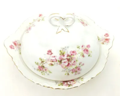 Antique Haviland Limoges covered butter dish featuring a delicate pink rose pattern, scalloped edges, and gold-gilded accents.
