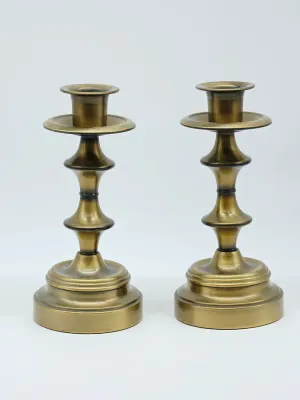 Pair of vintage brass candlesticks featuring a baluster-style turned stem and a stepped circular base.