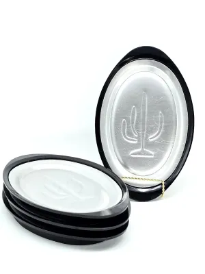 Set of vintage oval sizzler platters with black plastic underliners, featuring an embossed saguaro cactus design on the aluminum inserts.