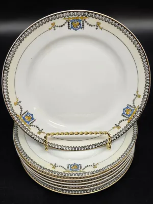 Stack of vintage porcelain plates featuring a gold-rimmed edge, a black and white geometric border, and delicate blue and yellow crest...