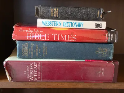 Stack of vintage reference books and Bibles, including a Cambridge Holy Bible, Webster's Dictionary, and Roget's Thesaurus,...
