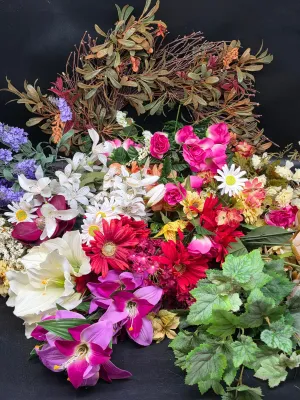 Large assortment of faux flowers and greenery, including a twig wreath, lilies, daisies, and roses in vibrant colors.