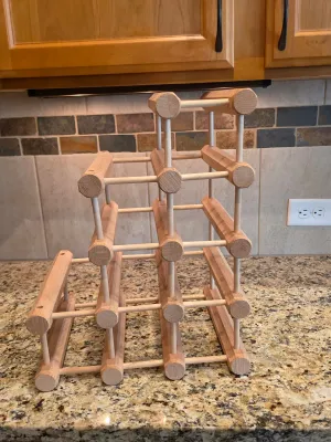Modular wooden wine rack with a natural finish, designed to hold up to ten bottles in a tiered configuration.