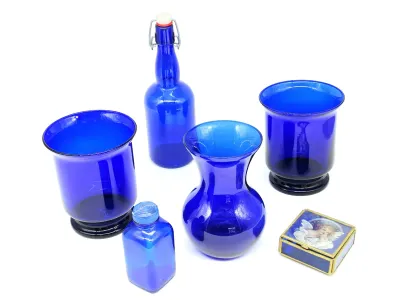 Collection of cobalt blue glassware, including two hurricane-style candle holders, a swing-top bottle, a small vase, a square bottle, and...