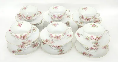 Vintage Haviland Limoges porcelain teacups and saucers, featuring a delicate pink floral pattern with gold-trimmed scalloped rims.