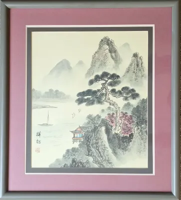 Framed Chinese ink and wash landscape painting depicting mountains, a river with boats, and a pavilion, presented in a double mat with a...