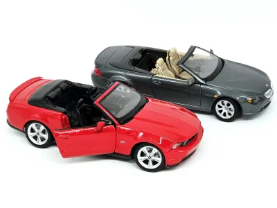 Two die-cast toy convertible cars, featuring a red Ford Mustang GT with an opening door and a dark grey BMW 6-Series, both in good...