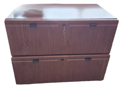 Two-drawer lateral filing cabinet with a faux-wood laminate finish, black recessed pulls, and a key in the top lock.