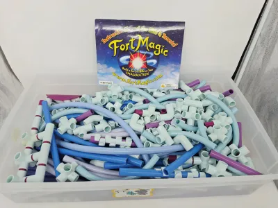 Fort Magic fort building kit with instruction manual, featuring a large assortment of colorful plastic rods and connectors in a clear...