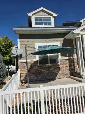 Large green cantilever patio umbrella with a dark grey metal frame, set up on a concrete patio.
