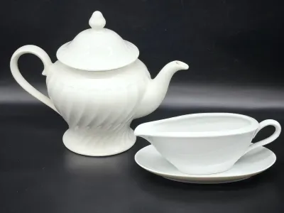 White ceramic teapot with a spiral fluted design and matching lid, shown alongside a white ceramic gravy boat with an attached underplate.