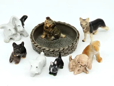 Collection of vintage miniature ceramic dog figurines, including Scottish Terriers and a puppy in a basket-weave dish.