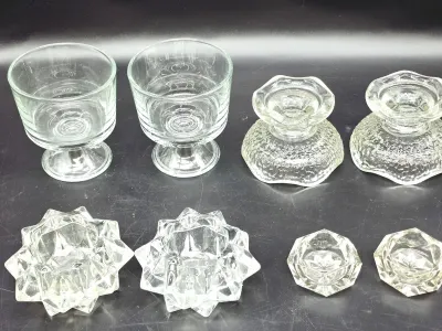 Assortment of vintage clear glass tableware, including pairs of footed dessert cups, textured candle holders, starburst-patterned votive...