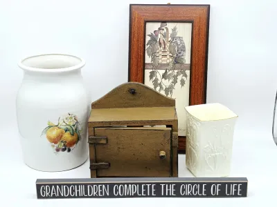 Assorted home decor items, including a white ceramic crock with fruit motif, a rustic wooden miniature cabinet, a framed print, a...