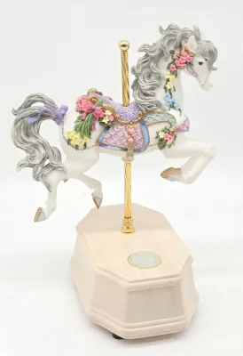 Vintage carousel horse music box featuring a white horse adorned with pastel flowers and a purple saddle, mounted on a brass pole and...