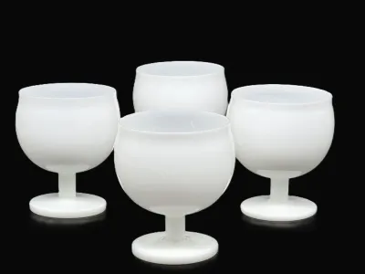 Set of four mid-century modern white milk glass goblets with rounded bowls and short stems, shown against a black background.