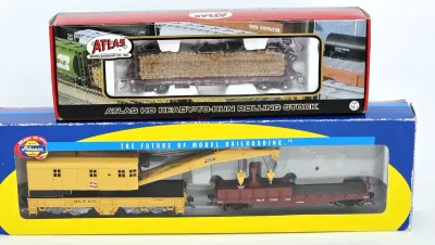 Two HO scale model train cars in their original packaging, featuring an Atlas log car and an Athearn Milwaukee Road crane car set.
