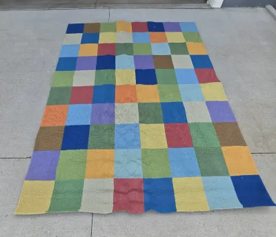 Large multi-colored checkerboard area rug featuring a grid of vibrant squares in shades of blue, green, yellow, orange, and red.
