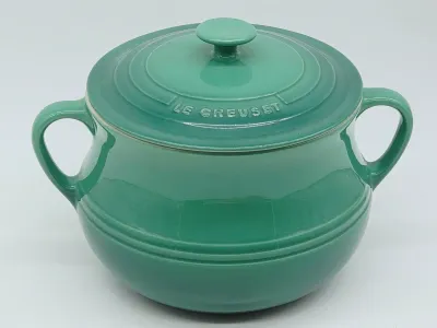 Le Creuset stoneware soup tureen with lid in a vibrant teal green glaze, featuring side handles and embossed branding on the lid.