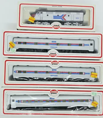 Four Model Power HO scale Amtrak train cars in their original boxes, including one locomotive and three passenger cars.