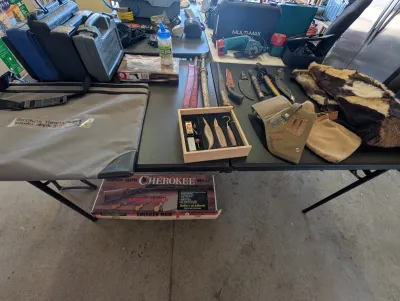 Assortment of outdoor and hunting gear, including a Thompson/Center Cherokee rifle kit box, various knives, a wood carving set, holsters,...