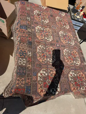 Vintage hand-knotted Persian or tribal area rug featuring geometric medallions in shades of brown, rust, cream, and blue.