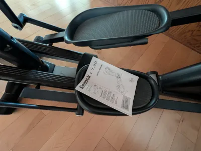 Reebok T 7.90 elliptical trainer showing the foot pedals and the original user's manual.