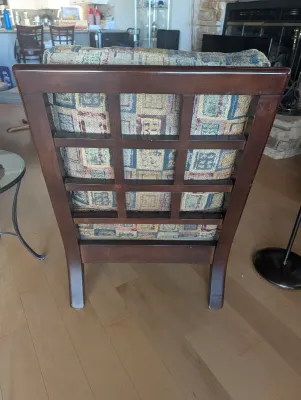 Backside of contemporary wooden armchair.  Wood pattern/color matches the 2 counter stools.