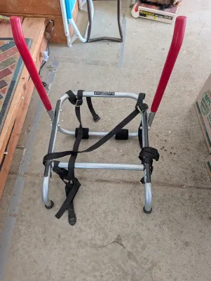 Fold-A-Rack aluminum luggage or gear carrier with red handles and black nylon securing straps.
