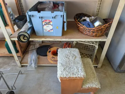 Assorted garage and household items, including a blue KeepBox storage container, a woven basket with towels, a carpeted pet step stool,...