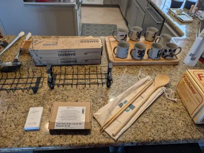 Assorted kitchenware and household items, including a set of eight stoneware mugs on a wooden tray, bamboo drawer dividers in original...